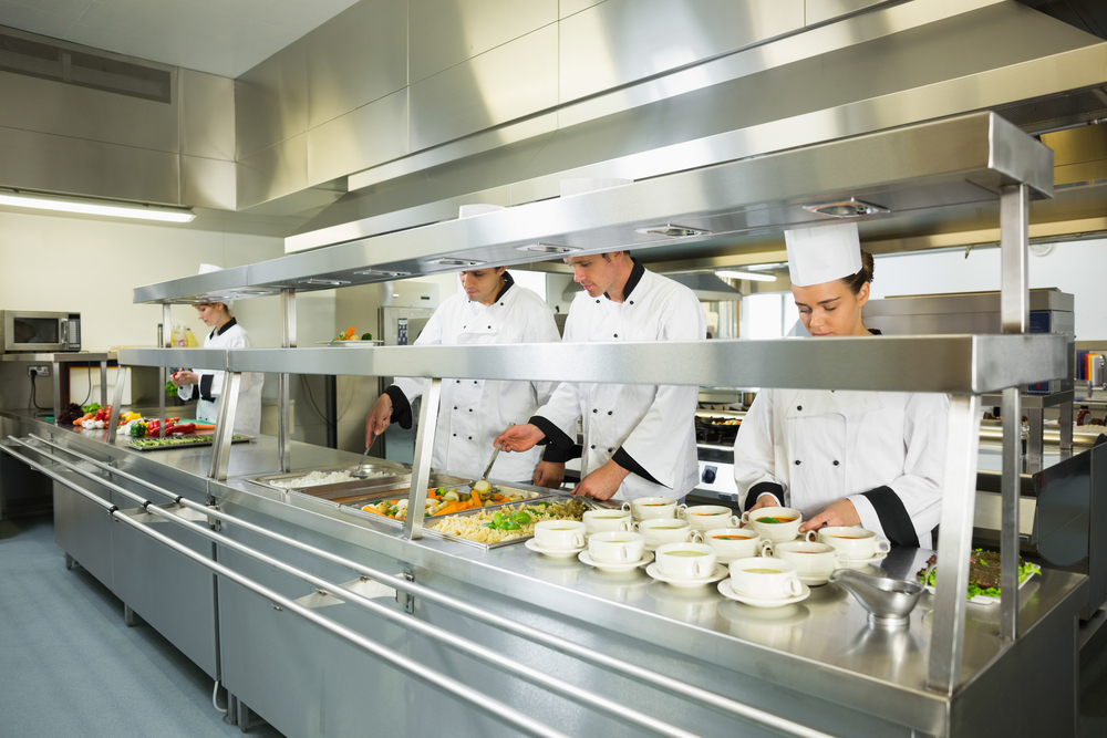 Four chefs working in a big kitchen at service time